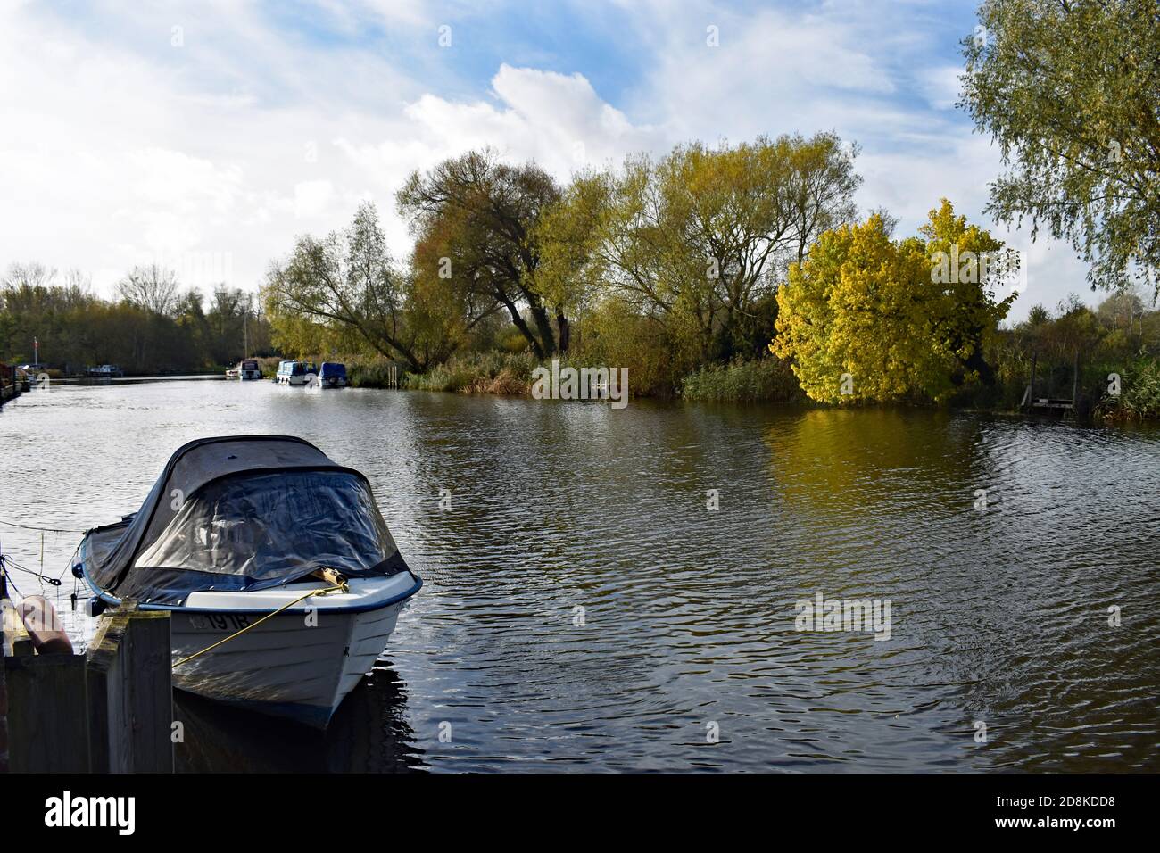 The River Waveney as it turns a bend  by the tow of Beccles in The Broads National Park, England.   Small pleasure boats are moored along the river. Stock Photo