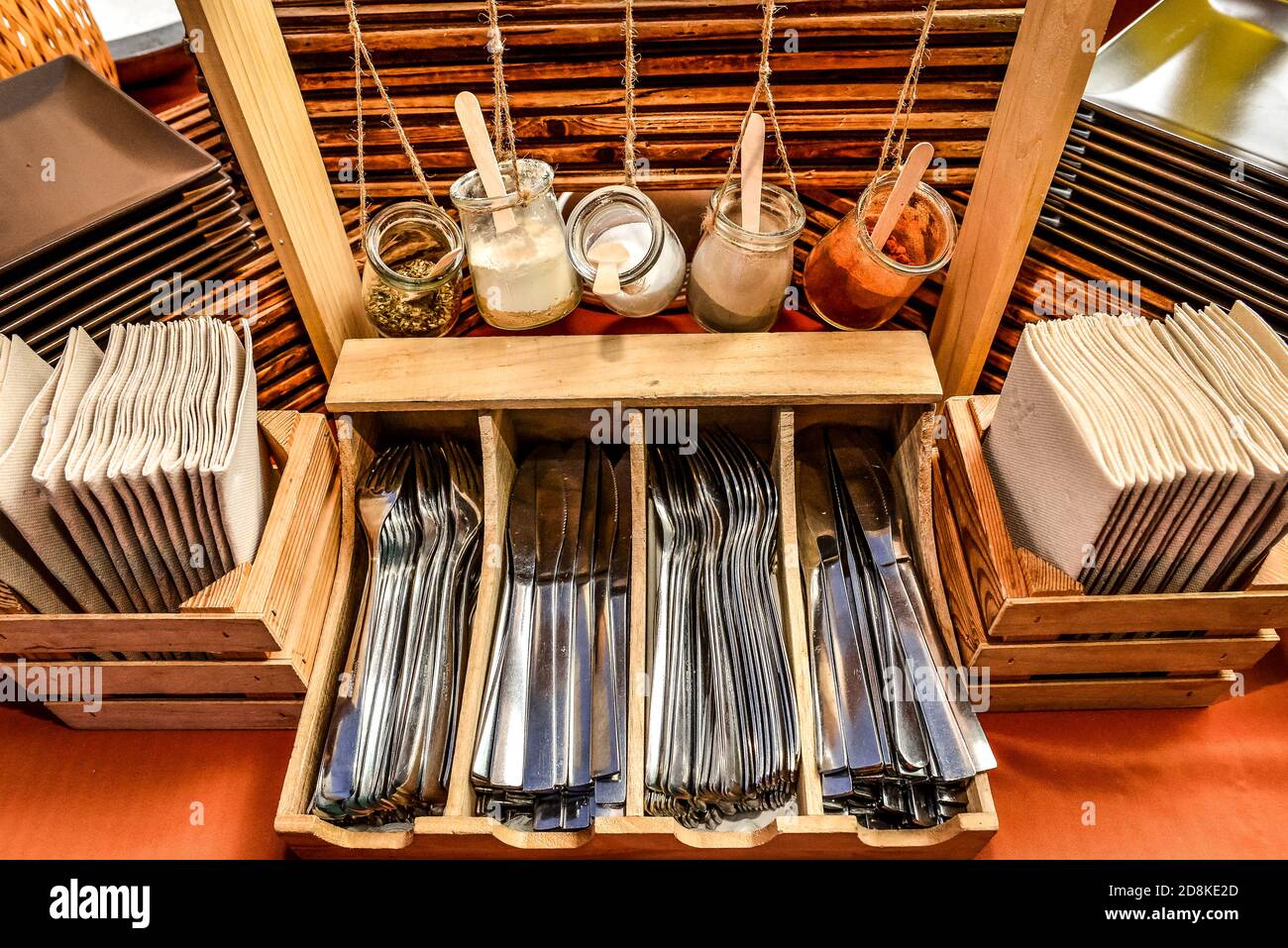 Neat arrangement of cutlery, napkin and hanging bottles of condiments at a cafe Stock Photo