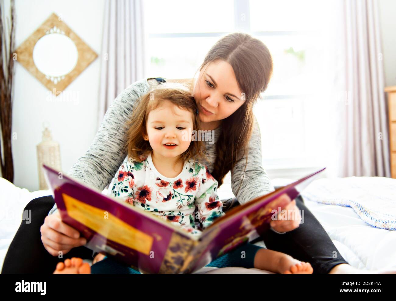 A mother and child daughter reading book in bed before going to sleep Stock Photo