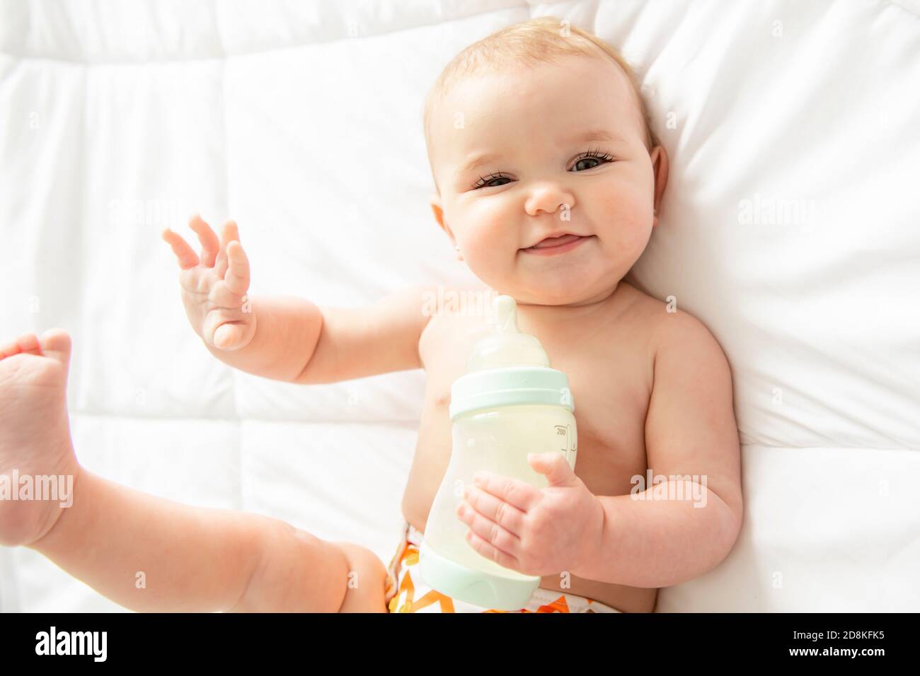 girl drinking bottle of milk laying on bed blond toddler Stock Photo - Alamy