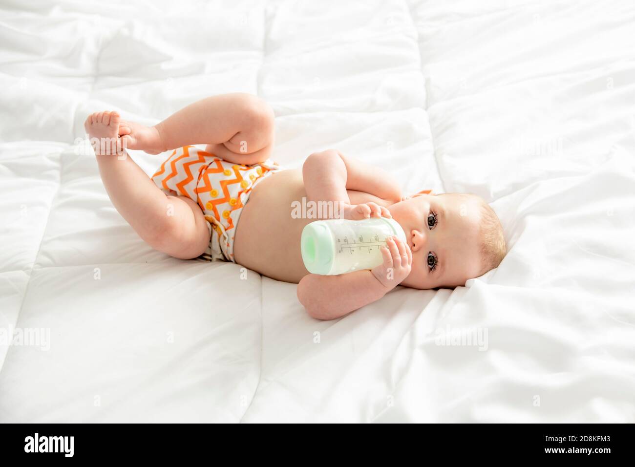 girl drinking bottle of milk laying on bed blond toddler Stock Photo - Alamy