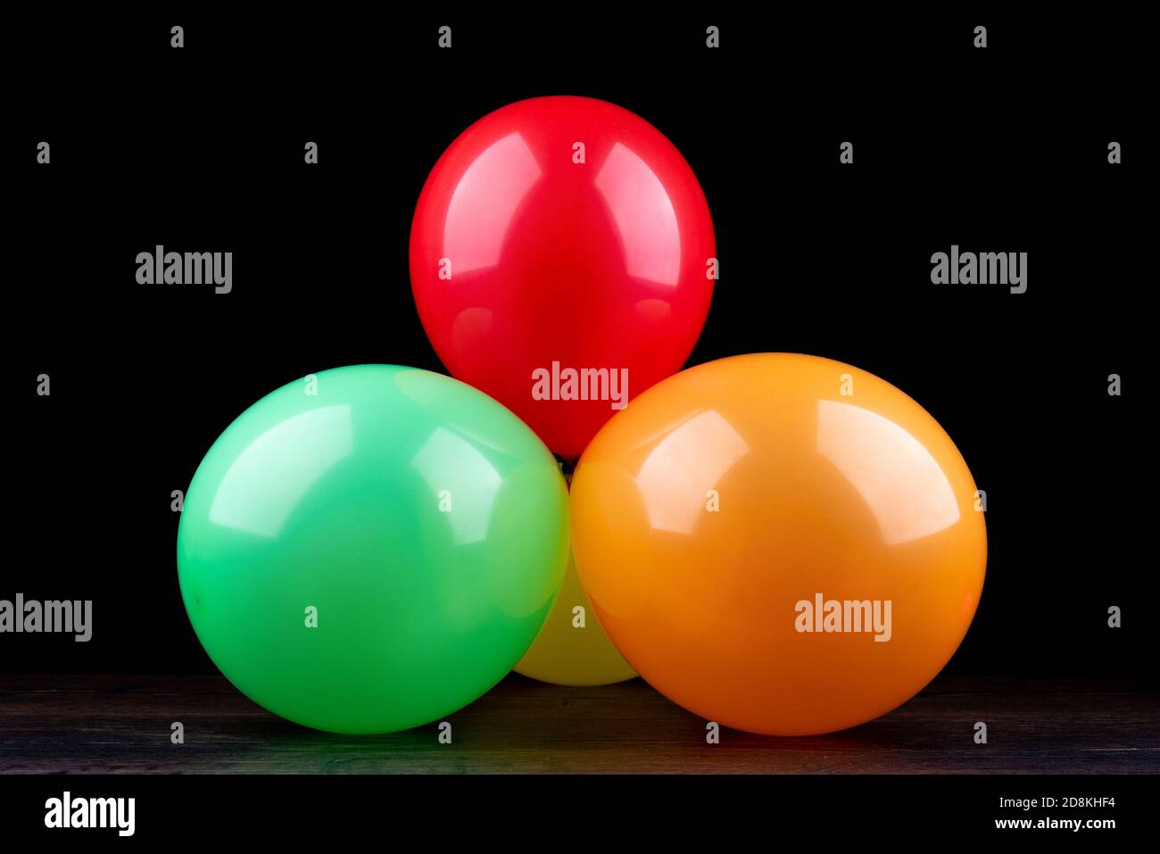 Bunch of colorful balloons on a wooden table against a black background ...