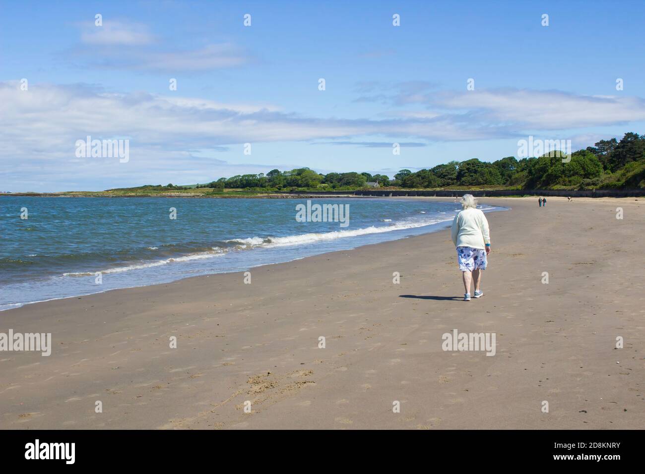6 June 2020 An elderly woman and others walk the beach for exercise during the Corona Virus pandemic at Ballyholme in Bangor Northern Ireland on a bre Stock Photo