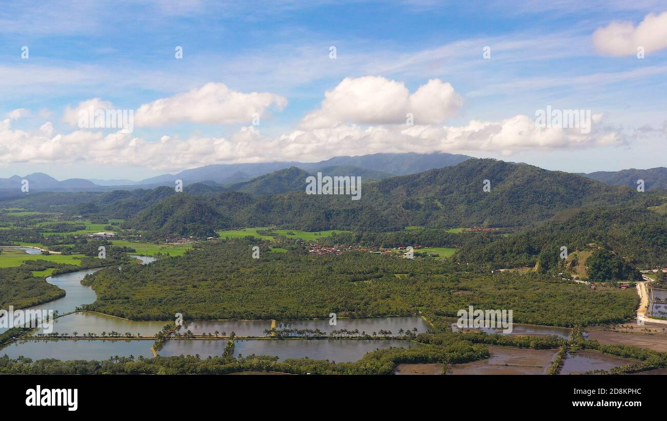 Tropical landscape: a town at the foot of mountains and hills covered with tropical vegetation and forest. Philippines, Mindanao. Surigao City. Stock Photo