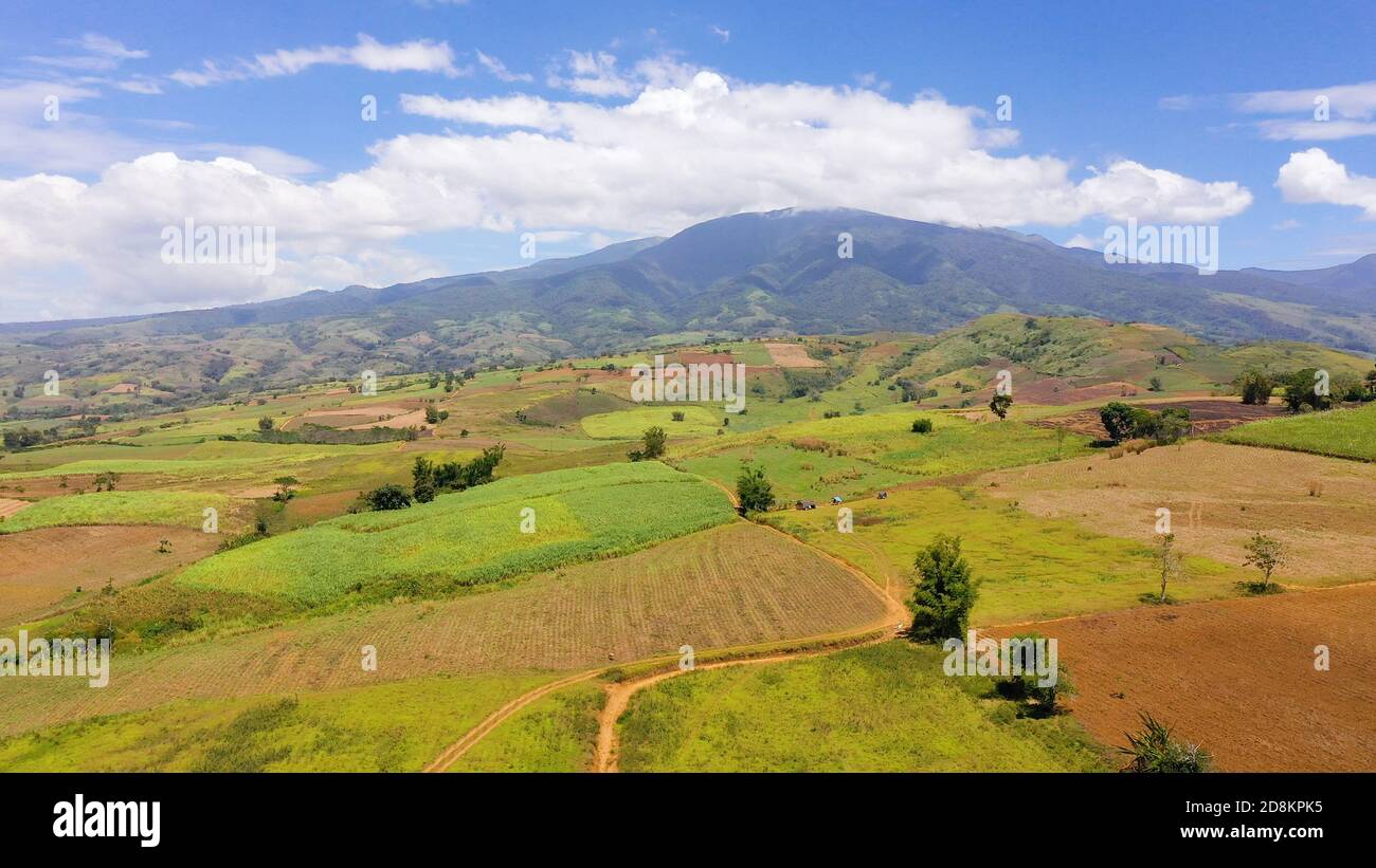 Fertile farmlands with growing crops and mountains with clouds against