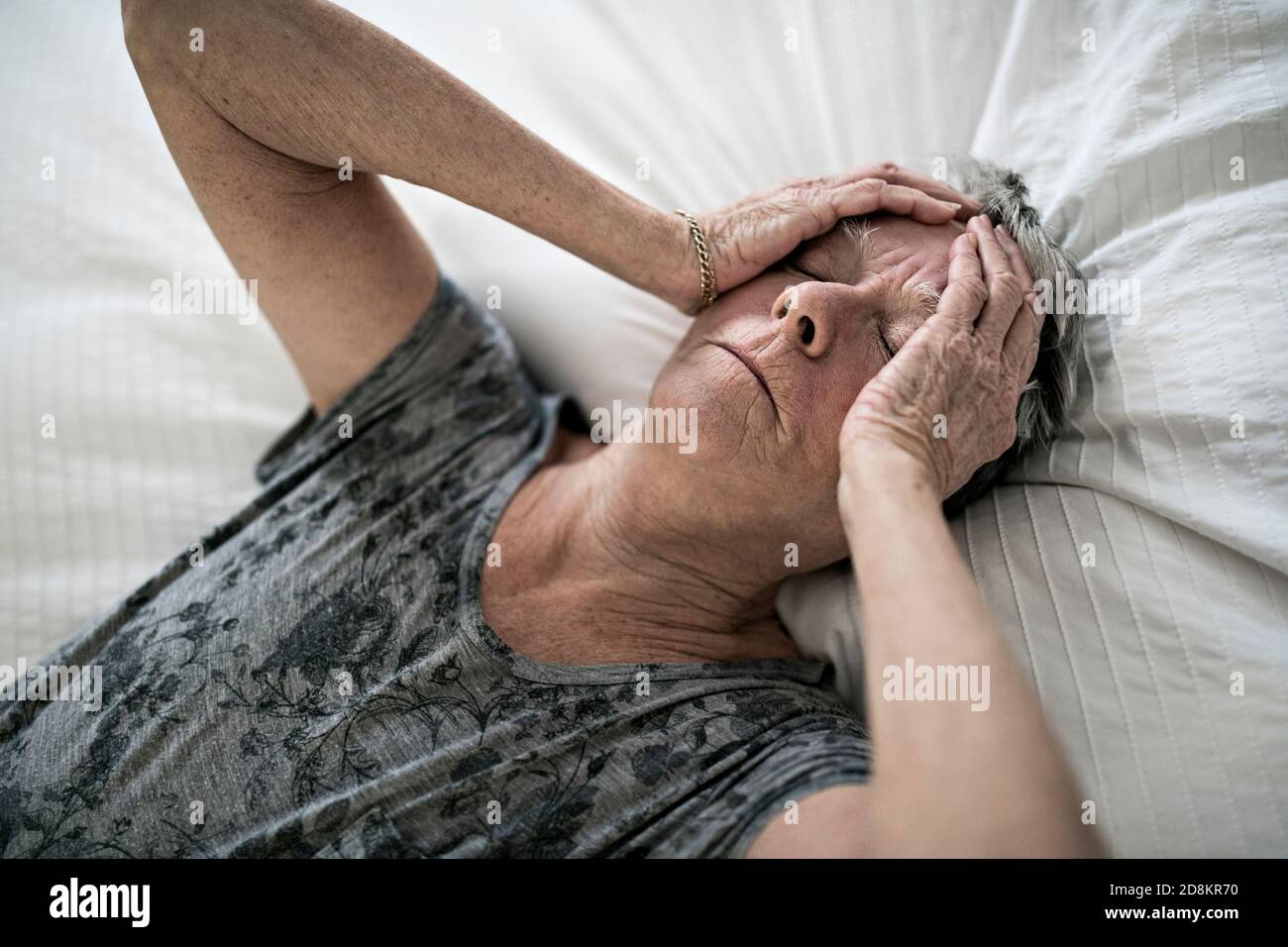 Senior aged woman on bed at home feeling sad Stock Photo