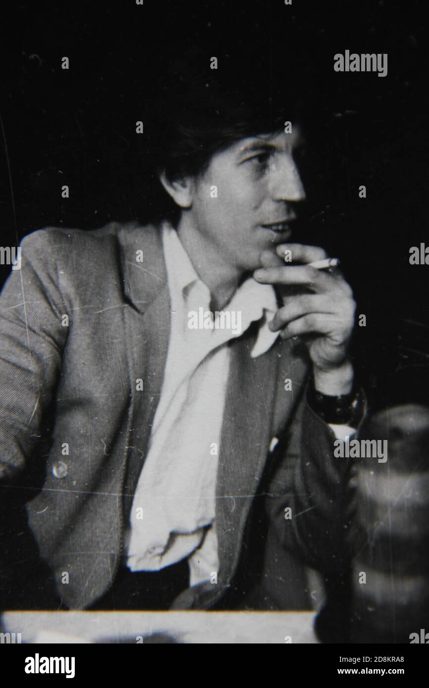 Fine 1970s vintage black and white photography of a young man smoking a cigarette and having a friendly conversation. Stock Photo