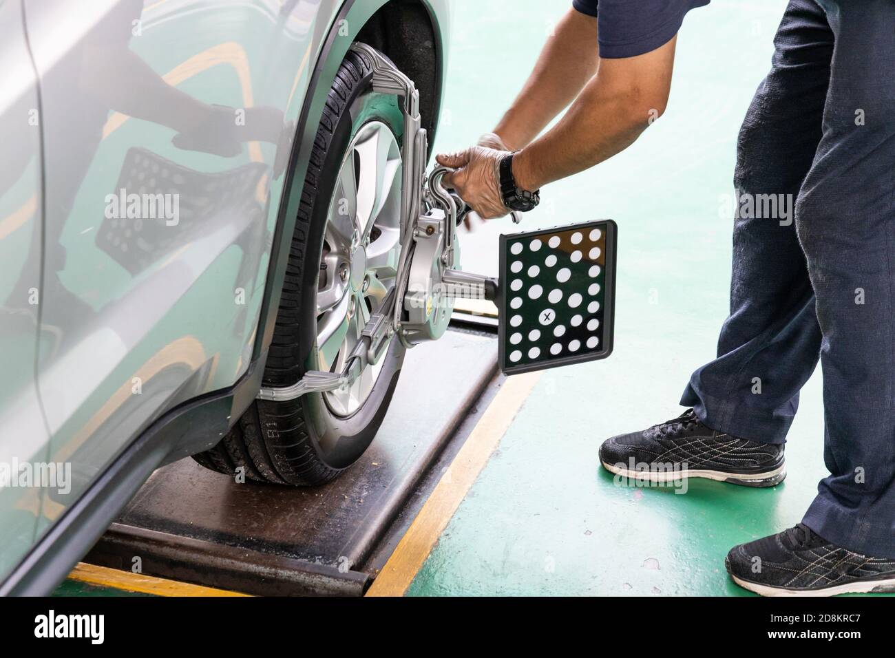 Worker attaching wheel alignment device equipment onto wheel car Stock