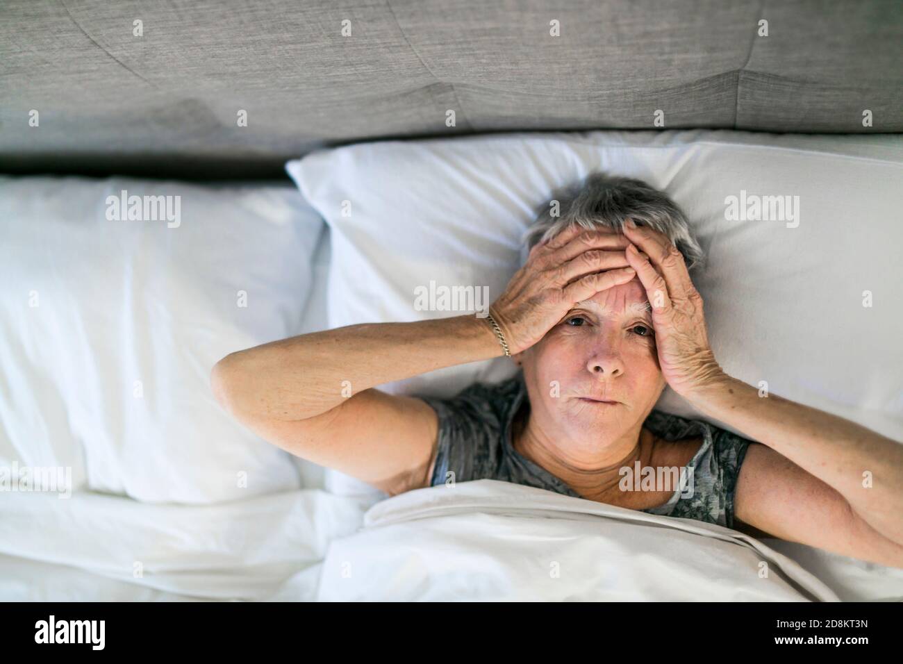 Senior aged woman on bed at home feeling sad Stock Photo