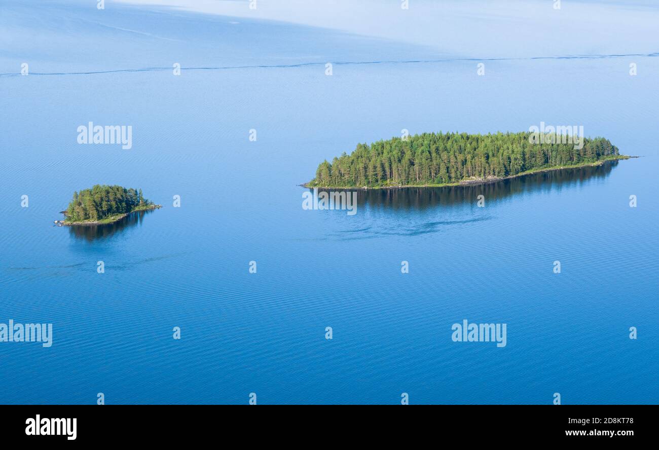 Scenic lake landscape with blue water and beautiful pine trees island at sunny summer day in National park Finland Stock Photo