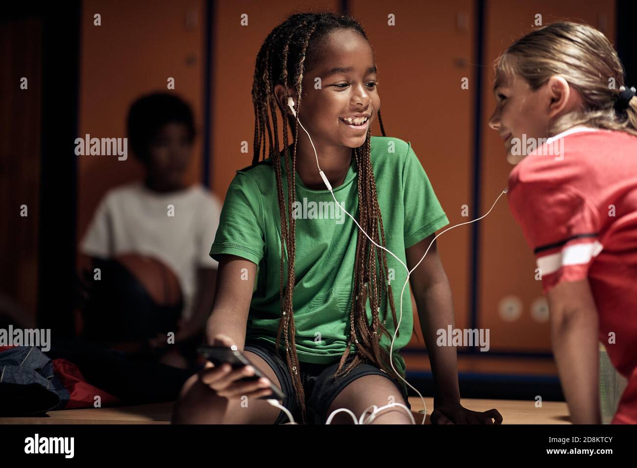 Kids listening to the music while waiting for a training at the locker room. Children team sport Stock Photo