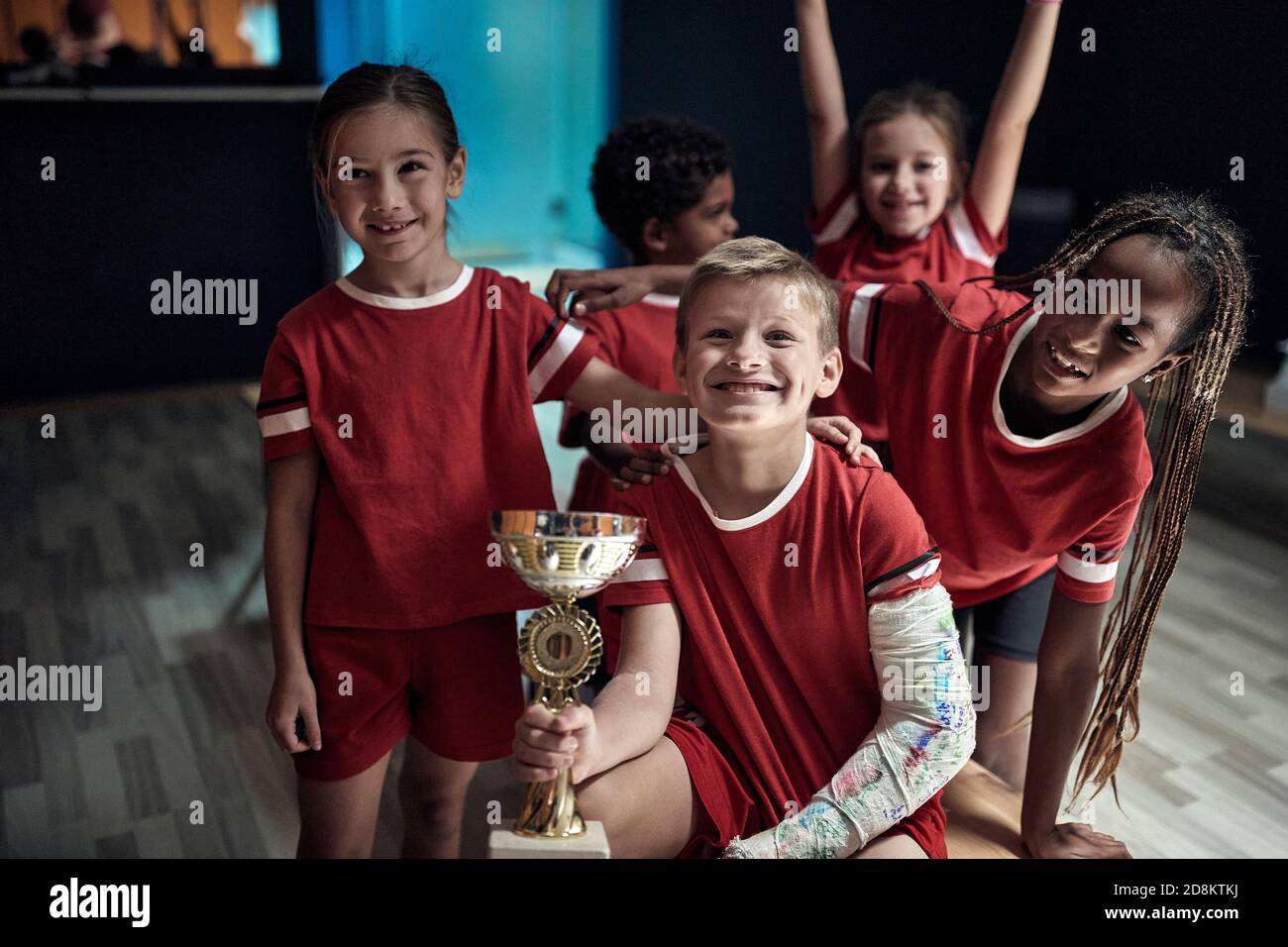 Kids team at the locker room posing with won trophy. Children team sport Stock Photo