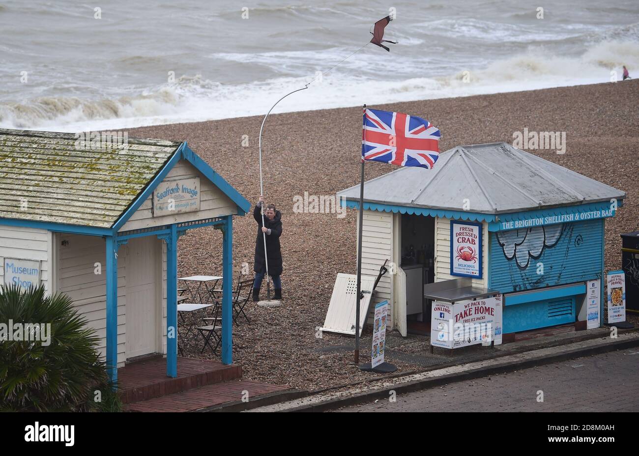 Brighton UK 31st October 2020 - A Brighton seafront stall holder battles the weather as she sets up for the day as Storm Aiden is forecast to affect parts of Britain with warnings of big winds and possible damage to property  : Credit Simon Dack / Alamy Live News Stock Photo