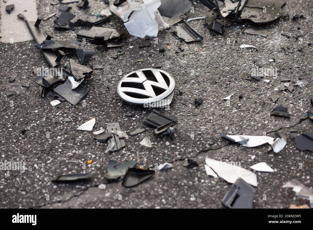 Volkswagen emblem between broken parts on the street after traffic accident Stock Photo