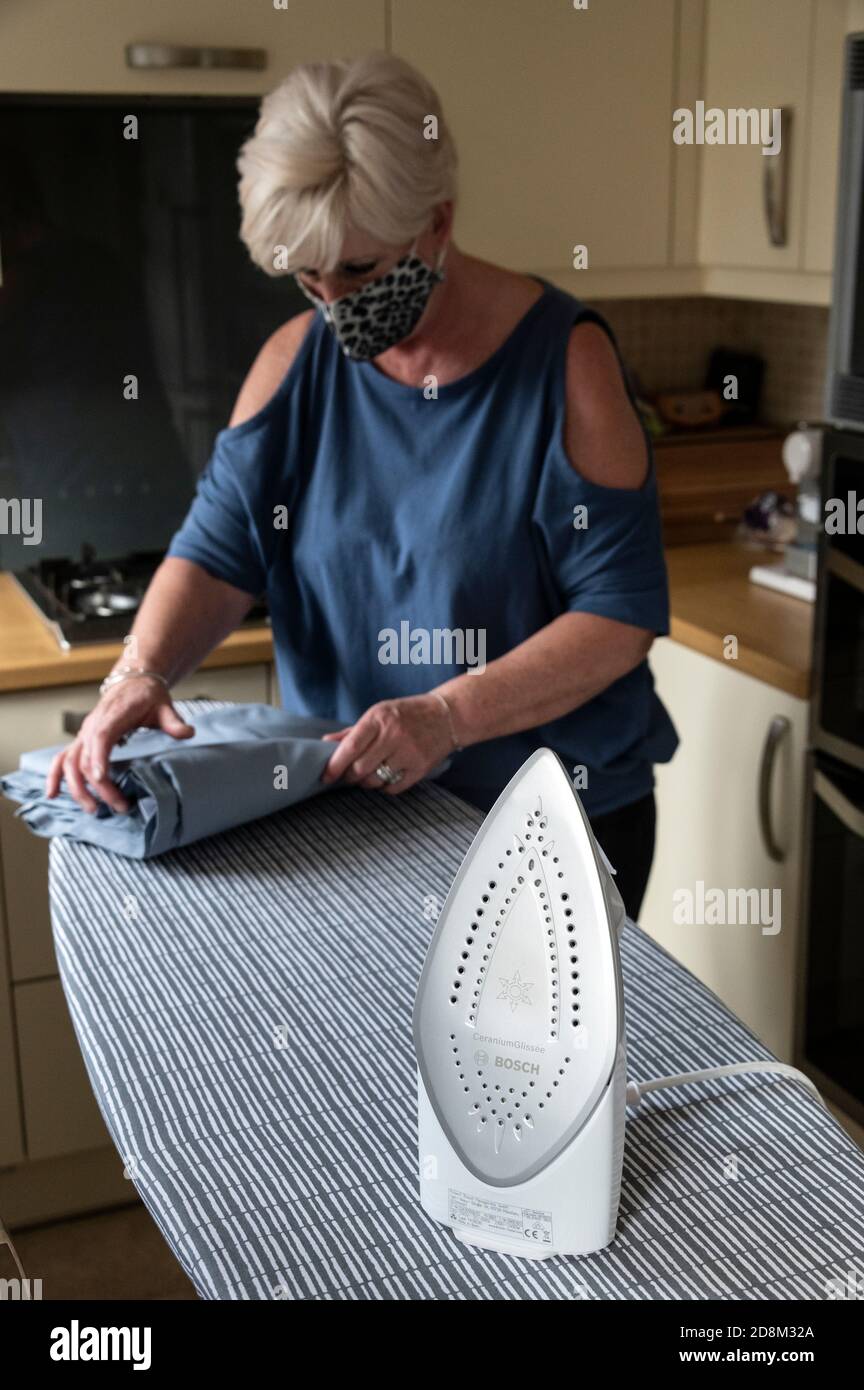 During the current covid 19 pandemic or epidemic, a self-employed house keeper or cleaner, wearing a protective face mask performing house work duties Stock Photo