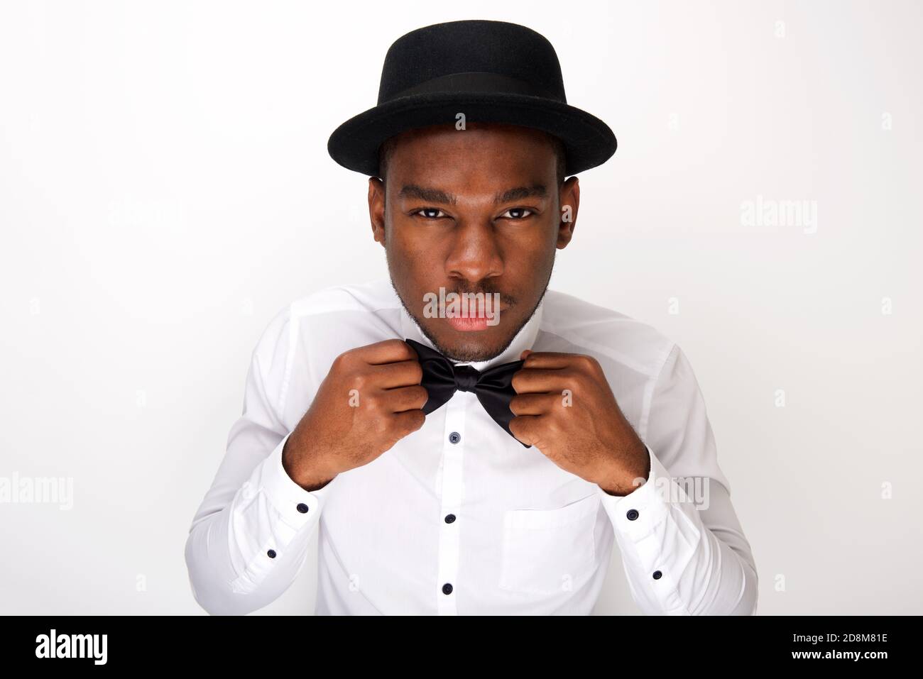 Portrait of male fashion model adjusting his bowtie by white background