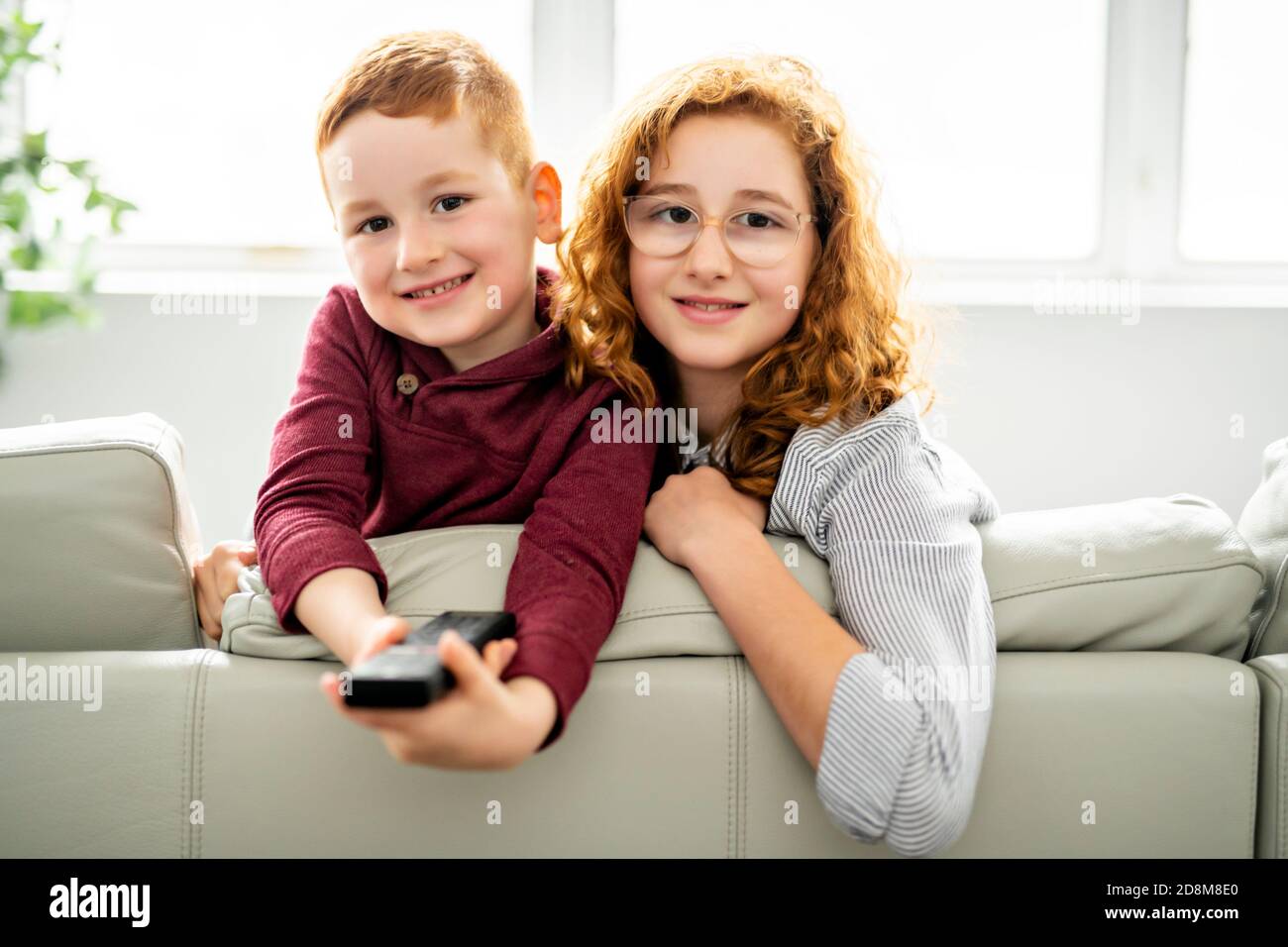 Happy girl and boy watching tv with remote control Stock Photo - Alamy