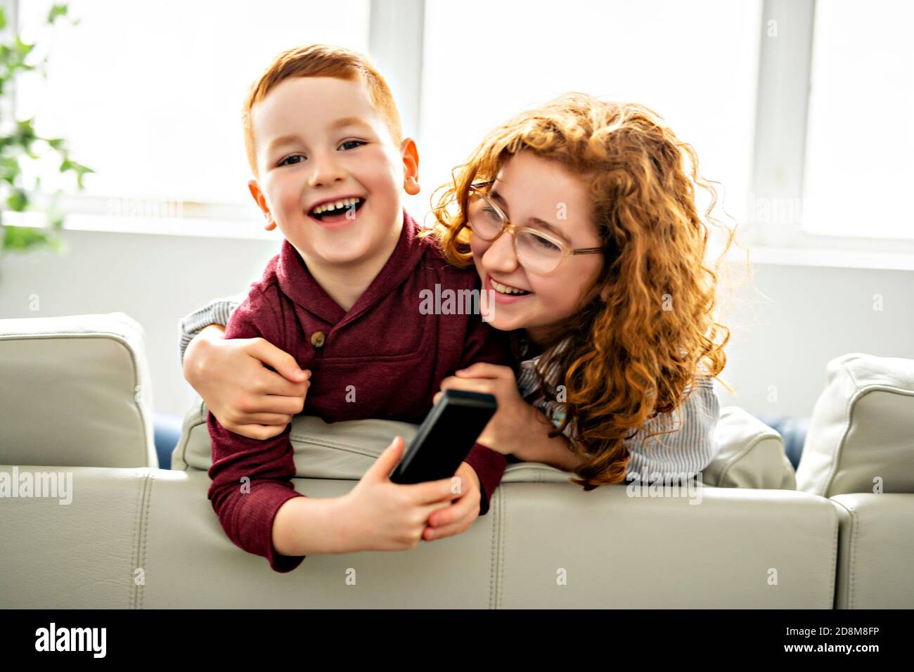 Happy girl and boy watching tv with remote control Stock Photo - Alamy