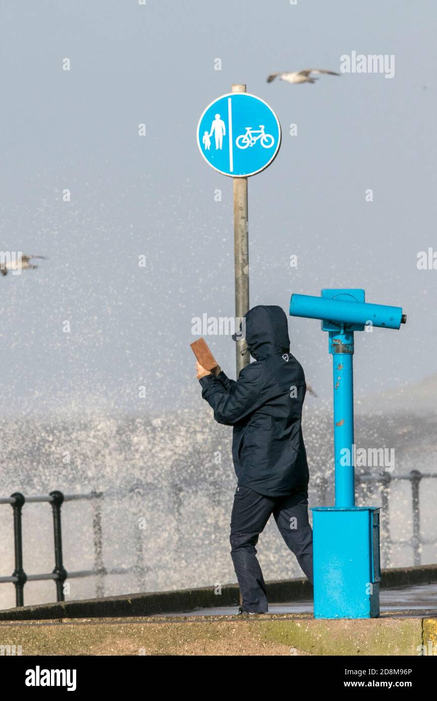 Crosby, Merseyside, 31 October 2020.  A man tries to take a photo of the incoming sea as storm force winds and high tide collide to batter the north west coastline at Crosby in Merseyside.   Credit: Cernan Elias/Alamy Live News Stock Photo