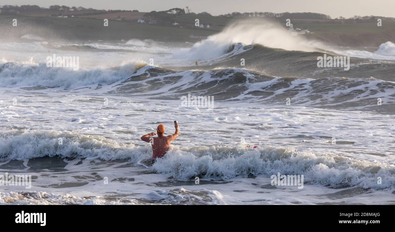 Myrtleville, Cork, Ireland. 31st October, 2020. A swimmer films the waves as they crash on to the coast during Storm Aiden in Myrtleville, Co. Cork, Ireland.- Credit; David Creedon / Alamy Live News Stock Photo