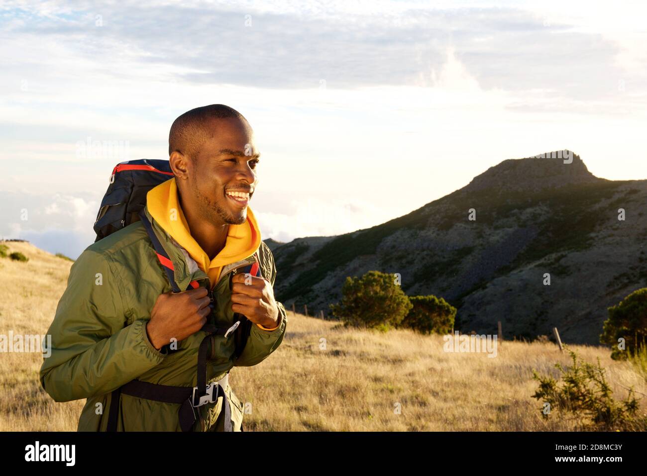 Side portrait of smiling young black man hiking in mountains with ...