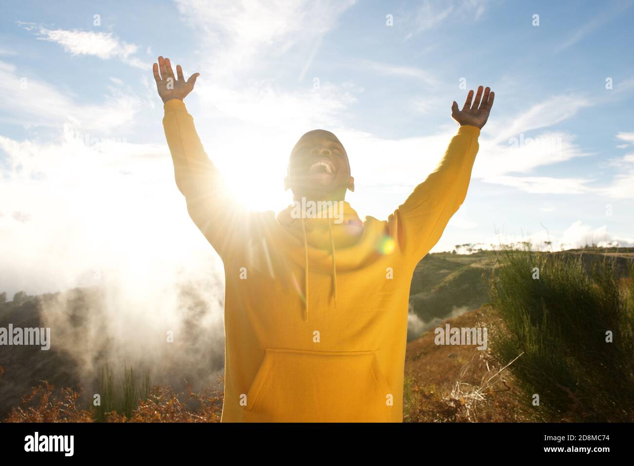 Portrait of happy young african american man with arms raised in air ...