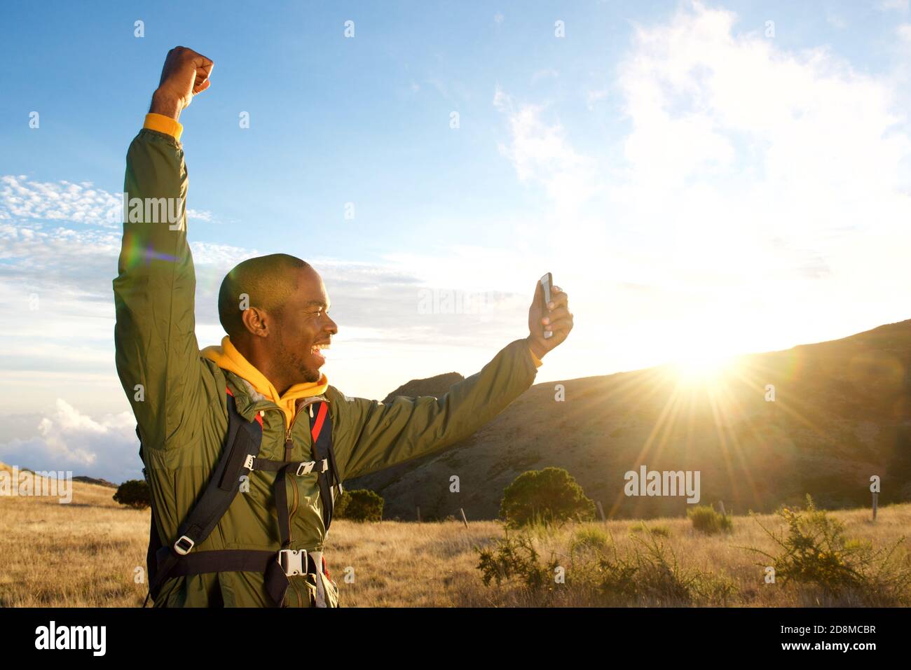 Profile portrait of happy man hiking in mountains with arm raised when ...