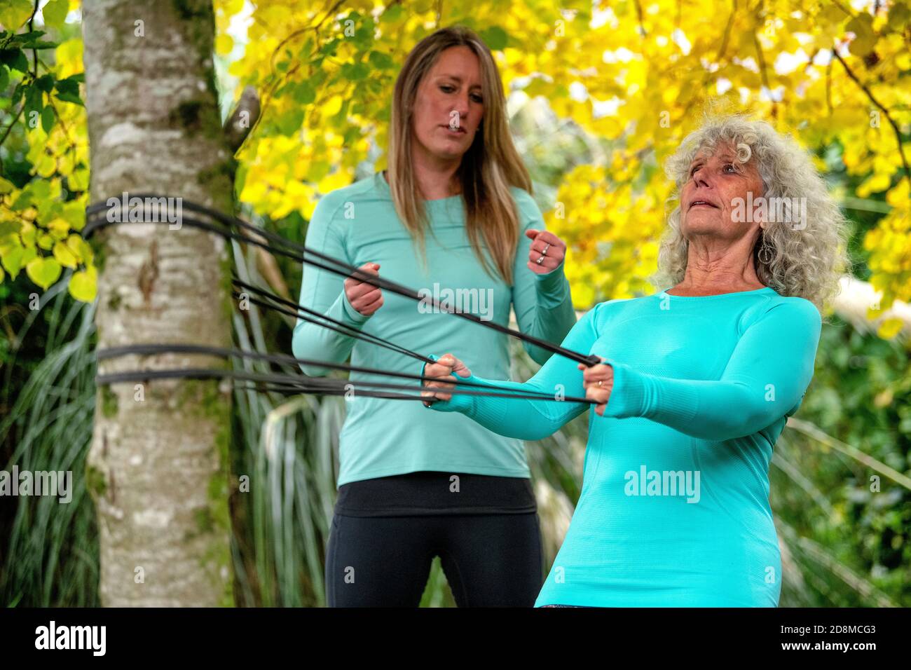 A woman in her late sixties exercises outdoors with a resistance band
