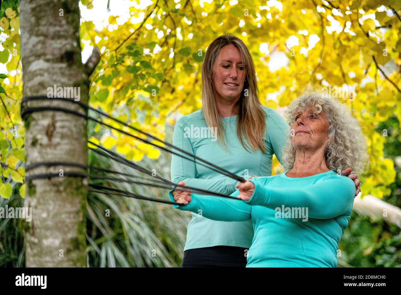 A woman in her late sixties exercises outdoors with a resistance band