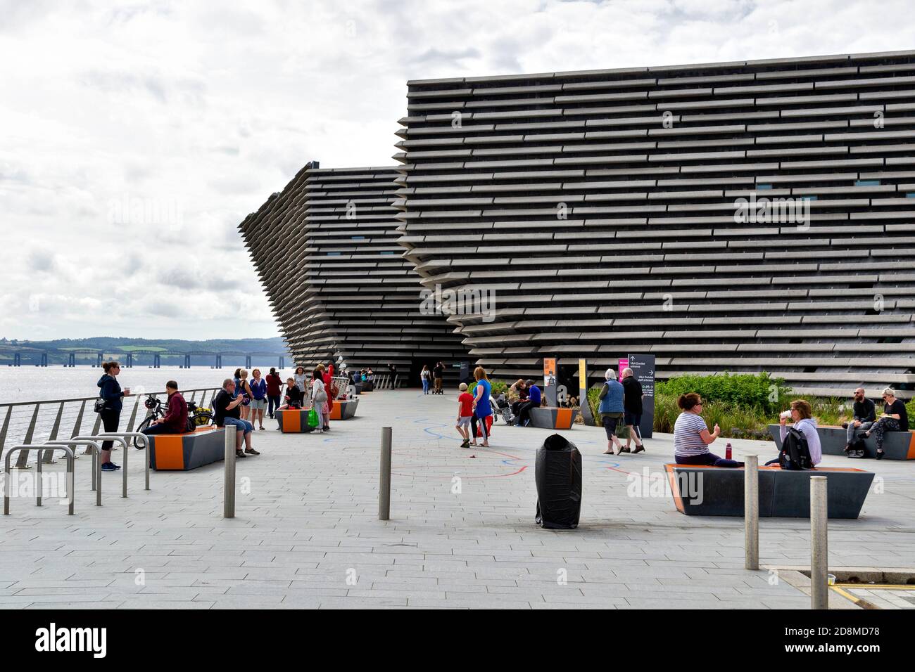 DUNDEE SCOTLAND THE V & A DESIGN MUSEUM  PEOPLE OUTSIDE THE BUILDING AND THE TAY RAILWAY BRIDGE IN THE DISTANCE Stock Photo
