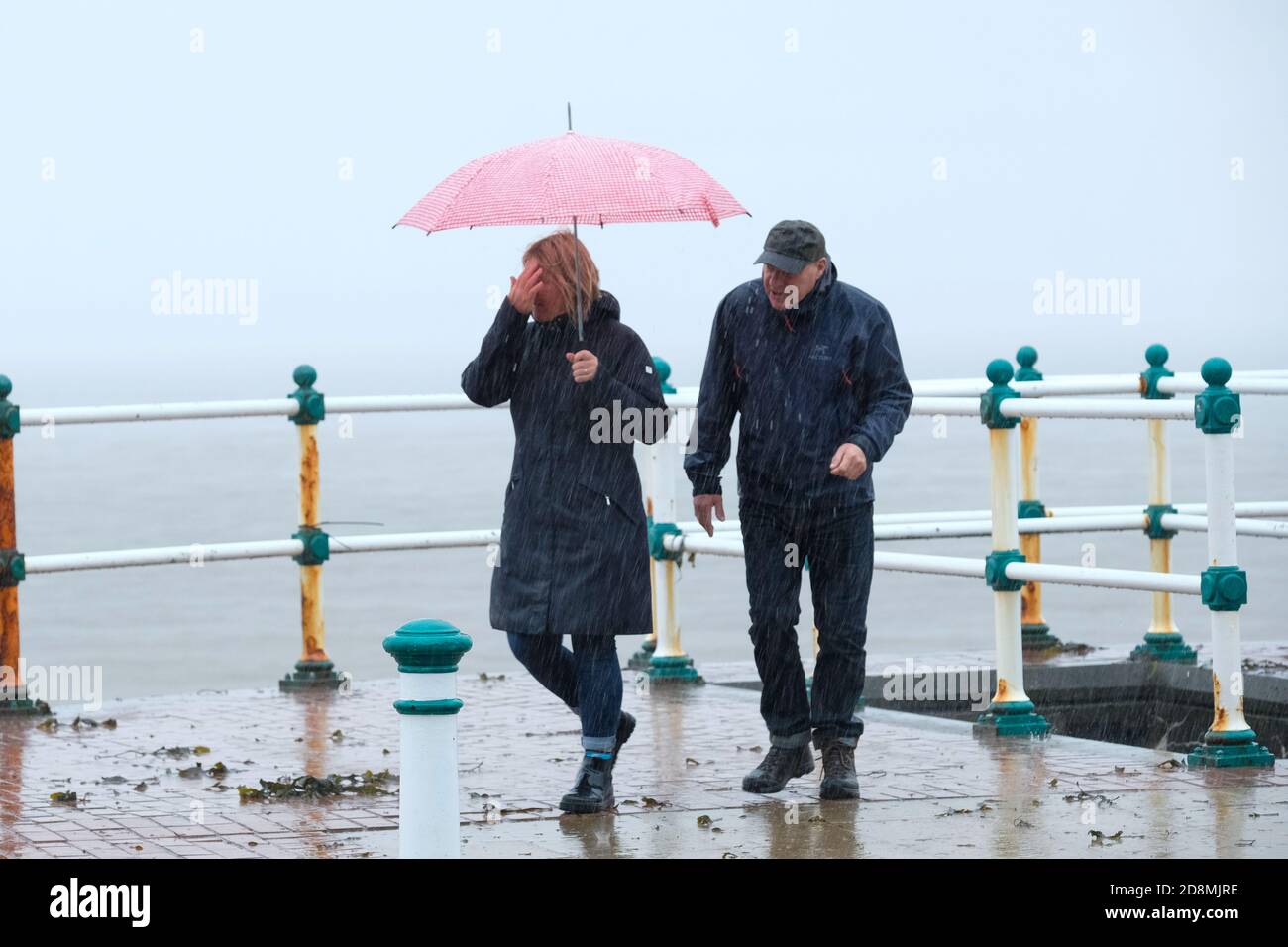 Stormy weather - Penarth, Wales UK. 31st October 2020.  The Met Office has issues a Yellow weather warning as storm Aiden batters the UK. Walkers brave the wind and rain on Penarth sea front. Stock Photo