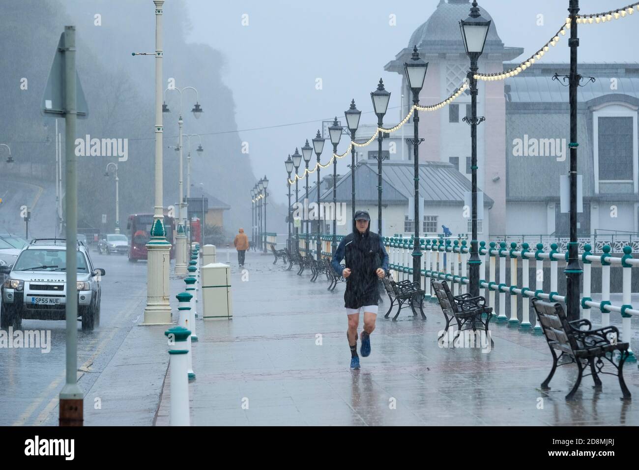 Stormy weather - Penarth, Wales UK. 31st October 2020.  The Met Office has issues a Yellow weather warning as storm Aiden batters the UK. A lone runner battles the wind and rain on Penarth sea front. Stock Photo