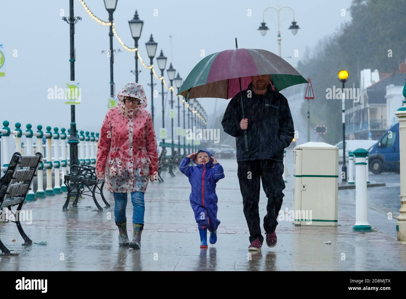 Stormy weather - Penarth, Wales UK. 31st October 2020.  The Met Office has issues a Yellow weather warning as storm Aiden batters the UK. A young child with his parents enjoying the wind and the rain on Penarth sea front. Stock Photo