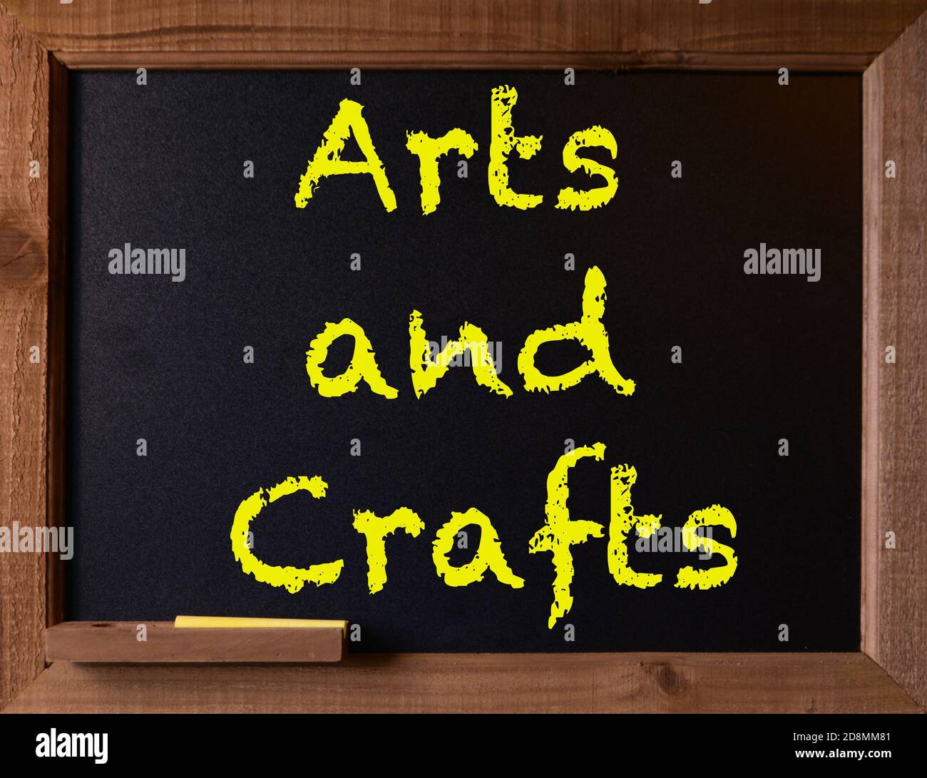 The message, 'Arts and Crafts' is written on a chalkboard, with wood border and yellow chalk. Stock Photo