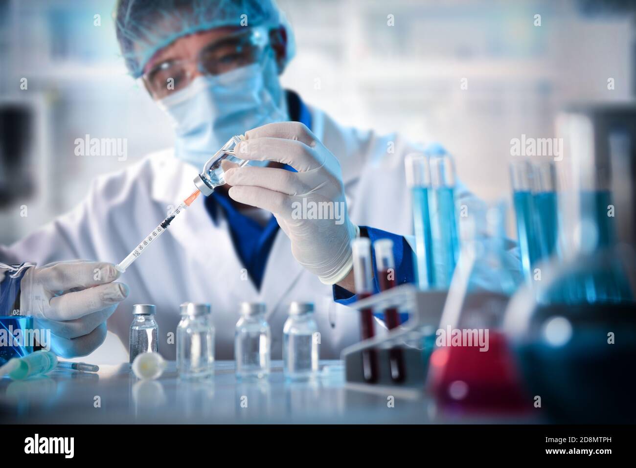 Virologist filling a syringe researching vaccine in laboratory bench. Horizontal composition. Front view. Stock Photo