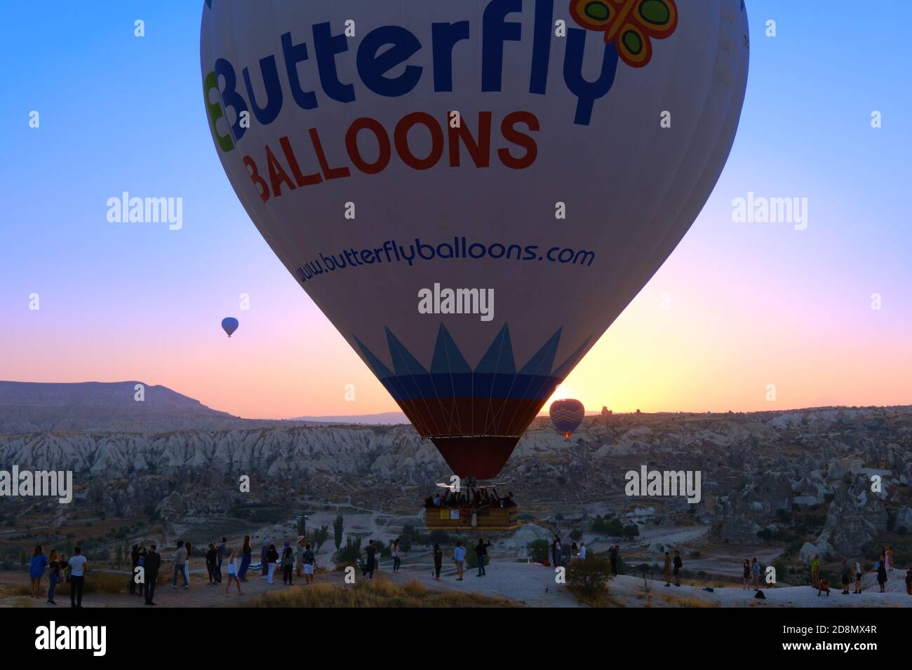 Big hot air balloon fly close to the hill with people, Cappadocia, Turkey Stock Photo