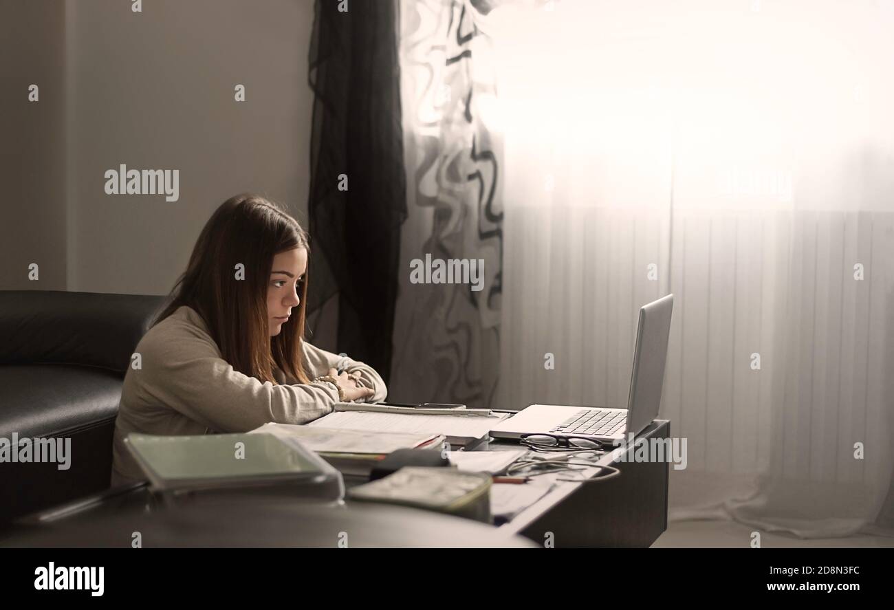 schoolgirl studying online from home unwillingly with a notebook, distance learning, laziness, frustration and tiredness, pessimism Stock Photo