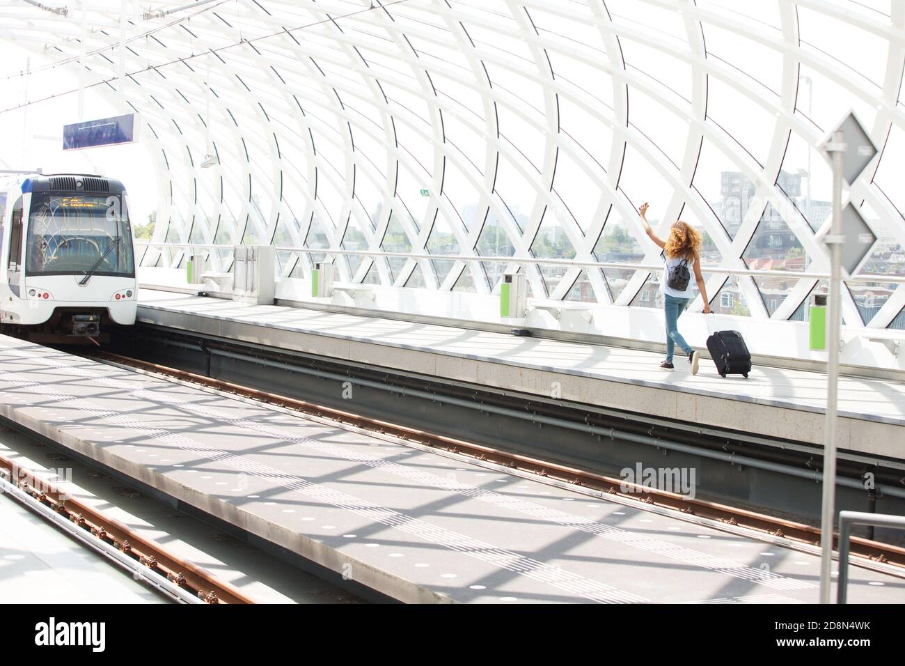 Portrait of young woman with bags running on platform in station to ...