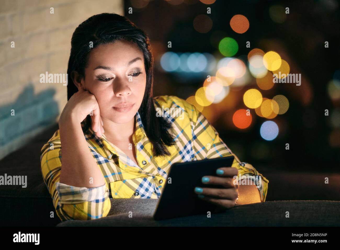 Young Woman Holding Ereader And Reading Ebook At Night Stock Photo