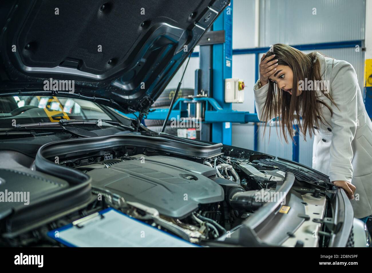 Female looking inside the hood of her car in a garage Stock Photo Alamy