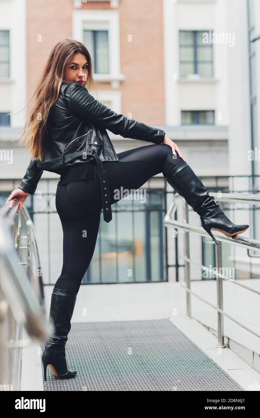 a beautiful blonde girl in urban casual clothing in the style of lifestyle  against the background of a geometric black house Stock Photo - Alamy