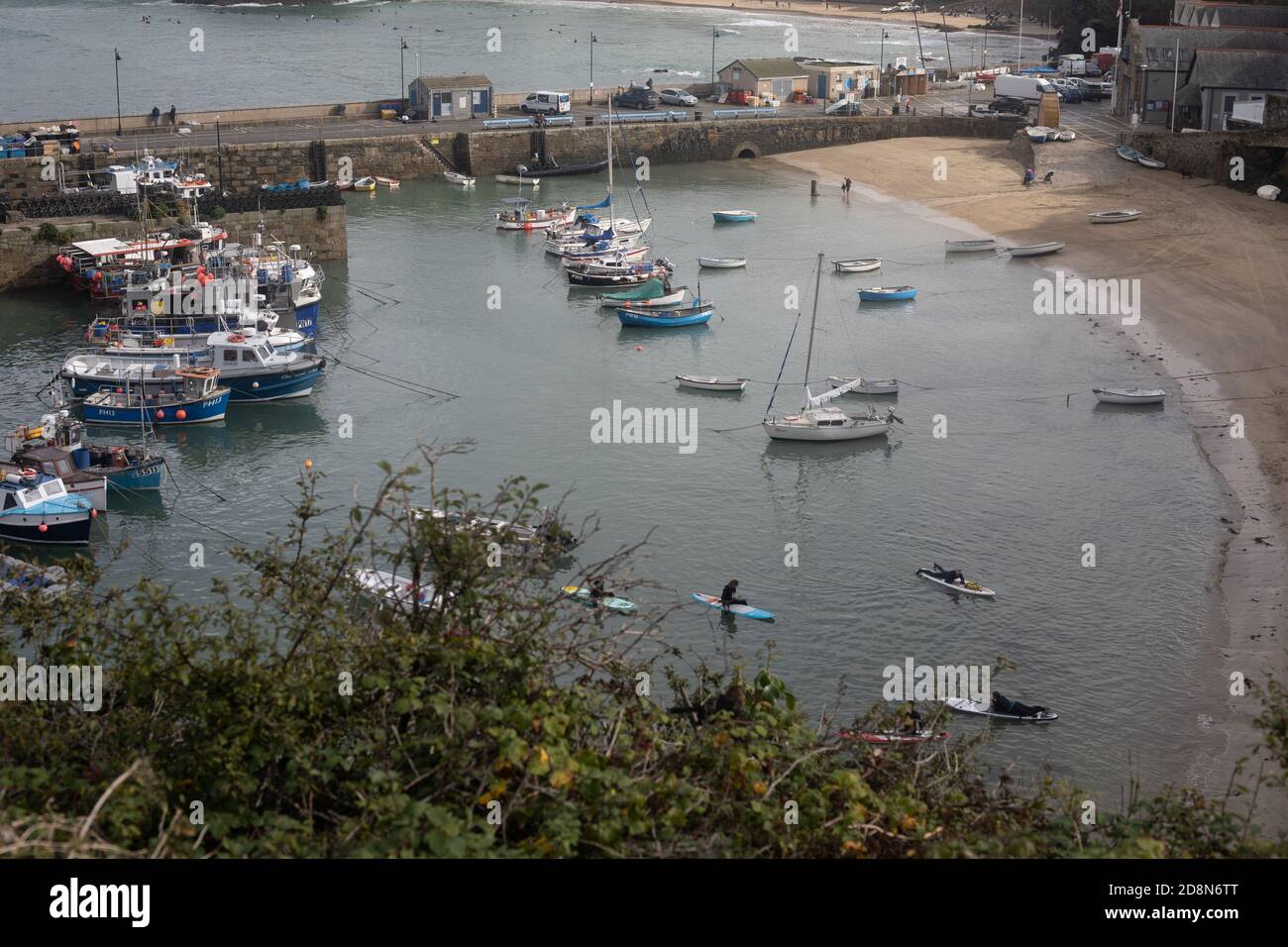 Fishing boats moored in Newquay Harbour, Cornwall with paddle boards. Stock Photo