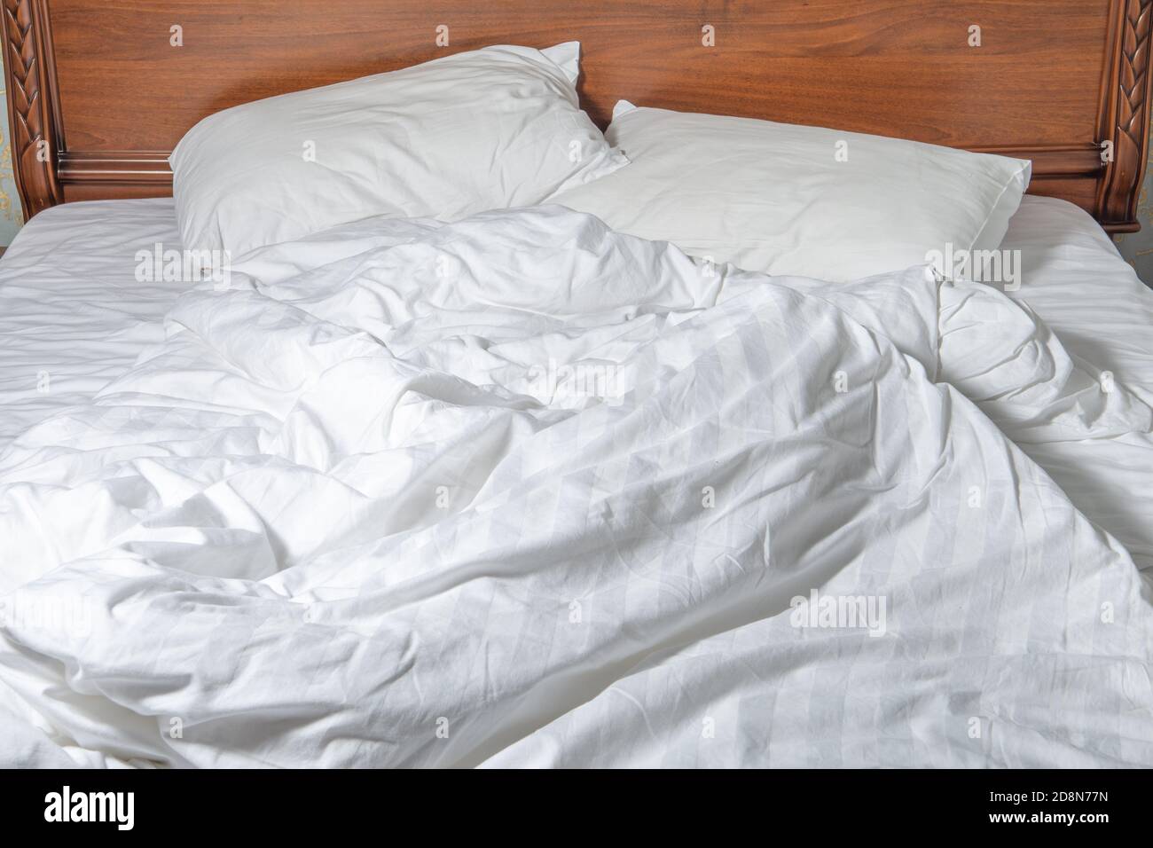 unmade bed with white linens. Unmade empty bed. Close up unmade bed sheet in the bedroom after night sleep Stock Photo