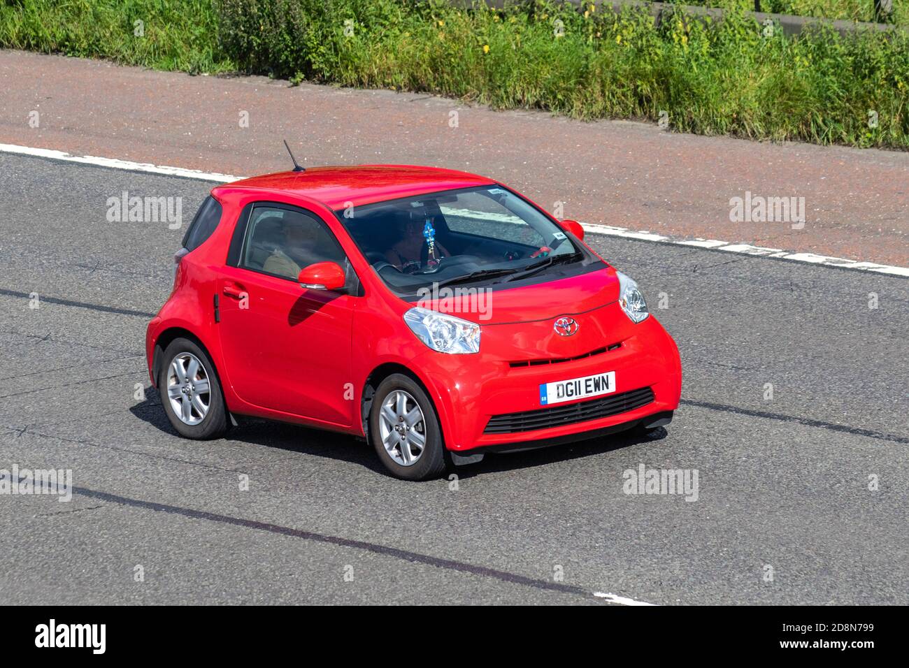2011 red Toyota IQ VVT-I; Vehicular traffic, moving vehicles, cars, vehicle driving on UK roads, motors, motoring on the M6 motorway highway UK road network Stock Photo
