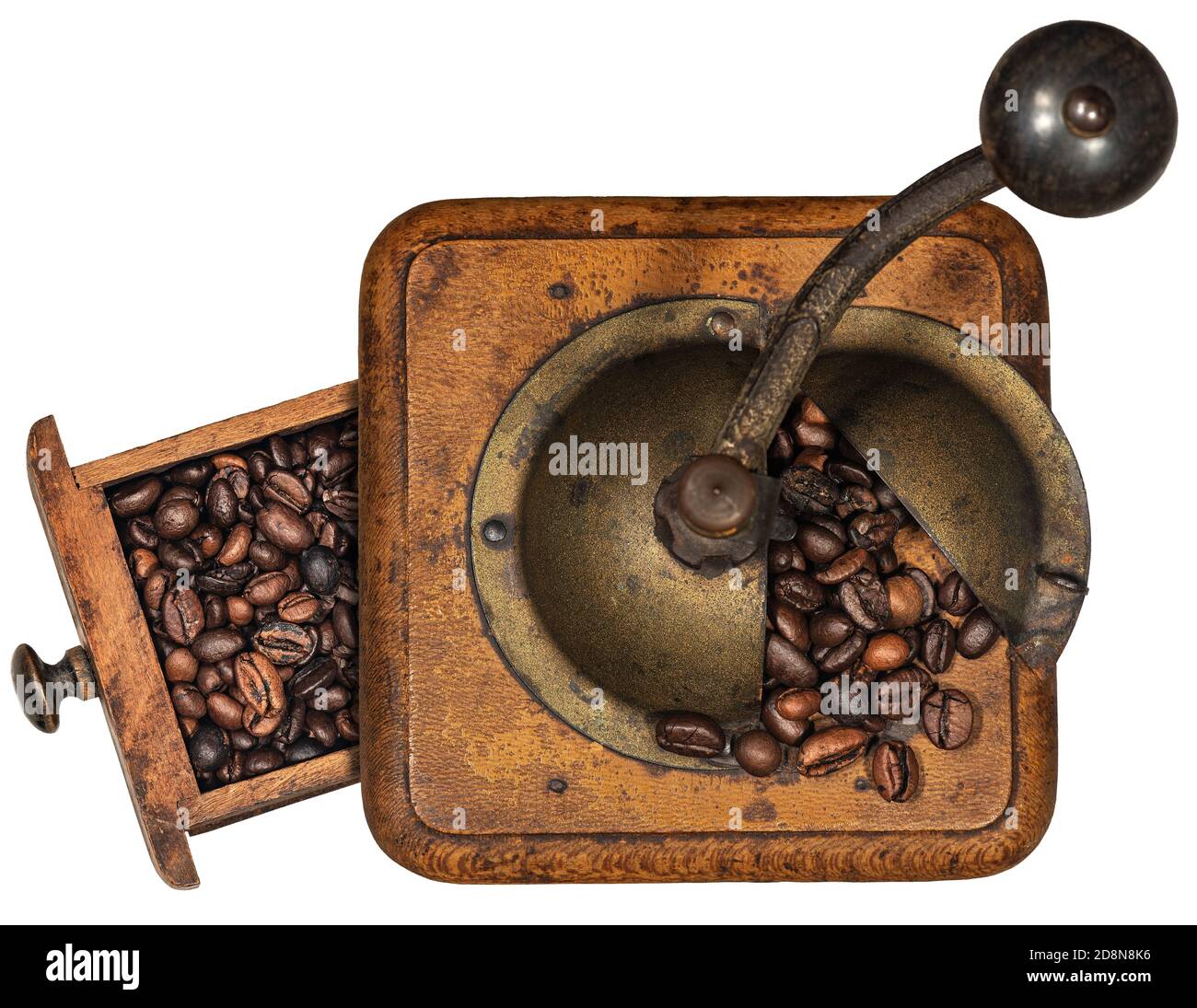Old manual coffee grinder made of metal and wood with roasted coffee beans isolated on white