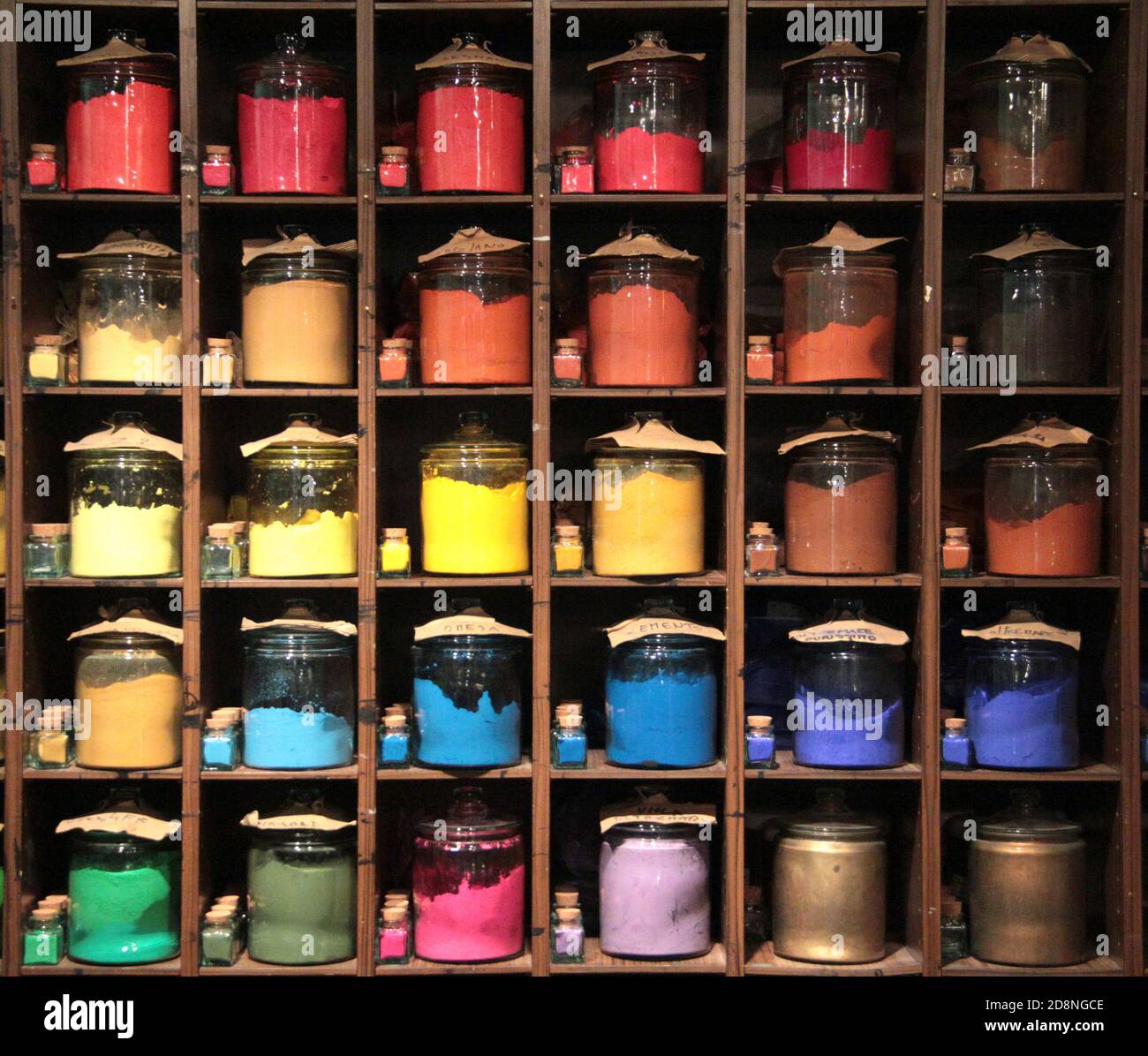 Colorful dye in glass containers in row on shelves in a paint shop for