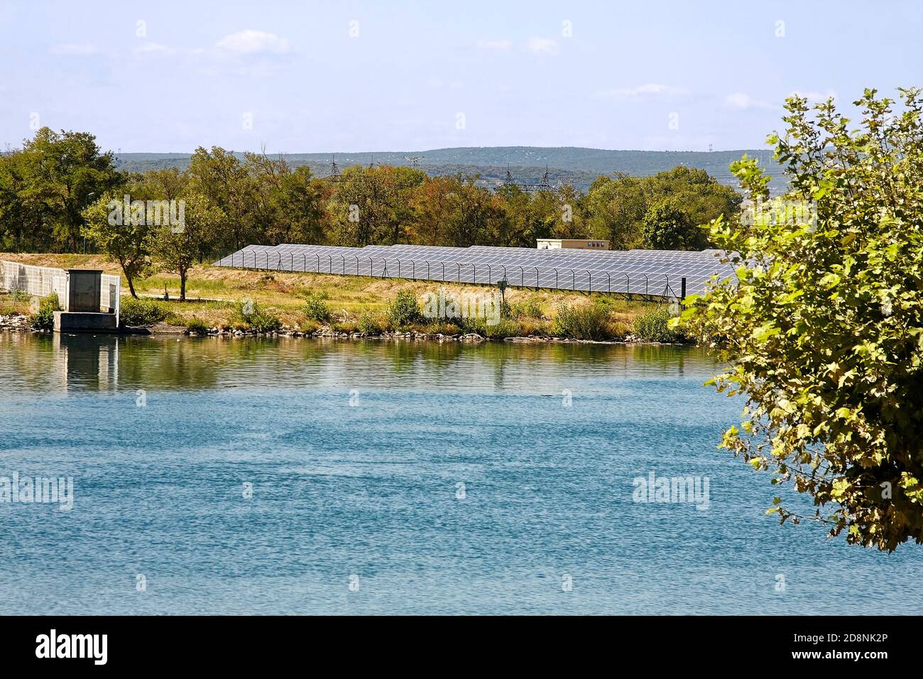 electrical power generation; many solar panels, energy production; power plant, business; water, vegetation, Rhone River, Provence; France; summer; ho Stock Photo