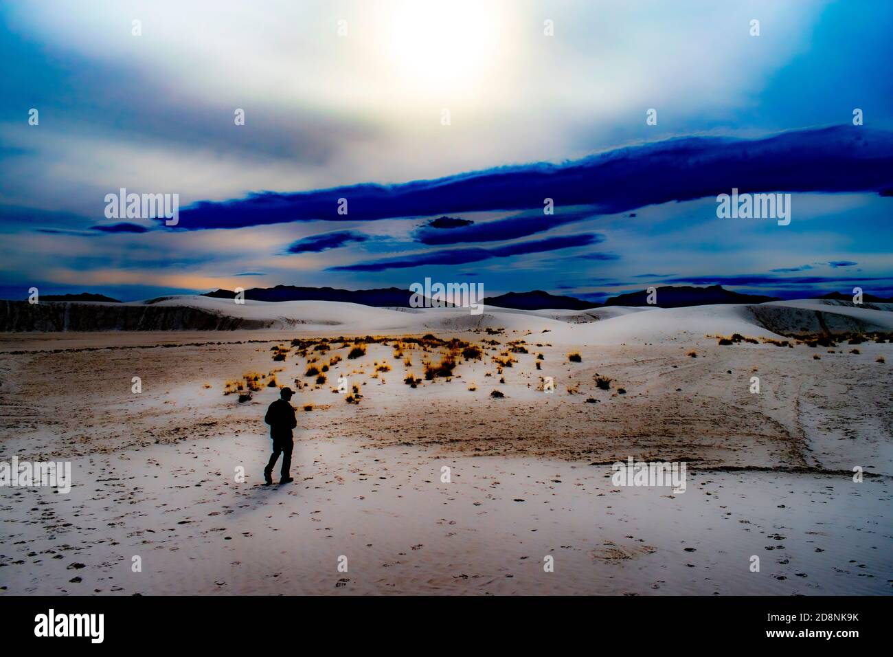 Silhouette of a person standing among the Sand Dunes of White Sands National Park with surreal colors. Stock Photo