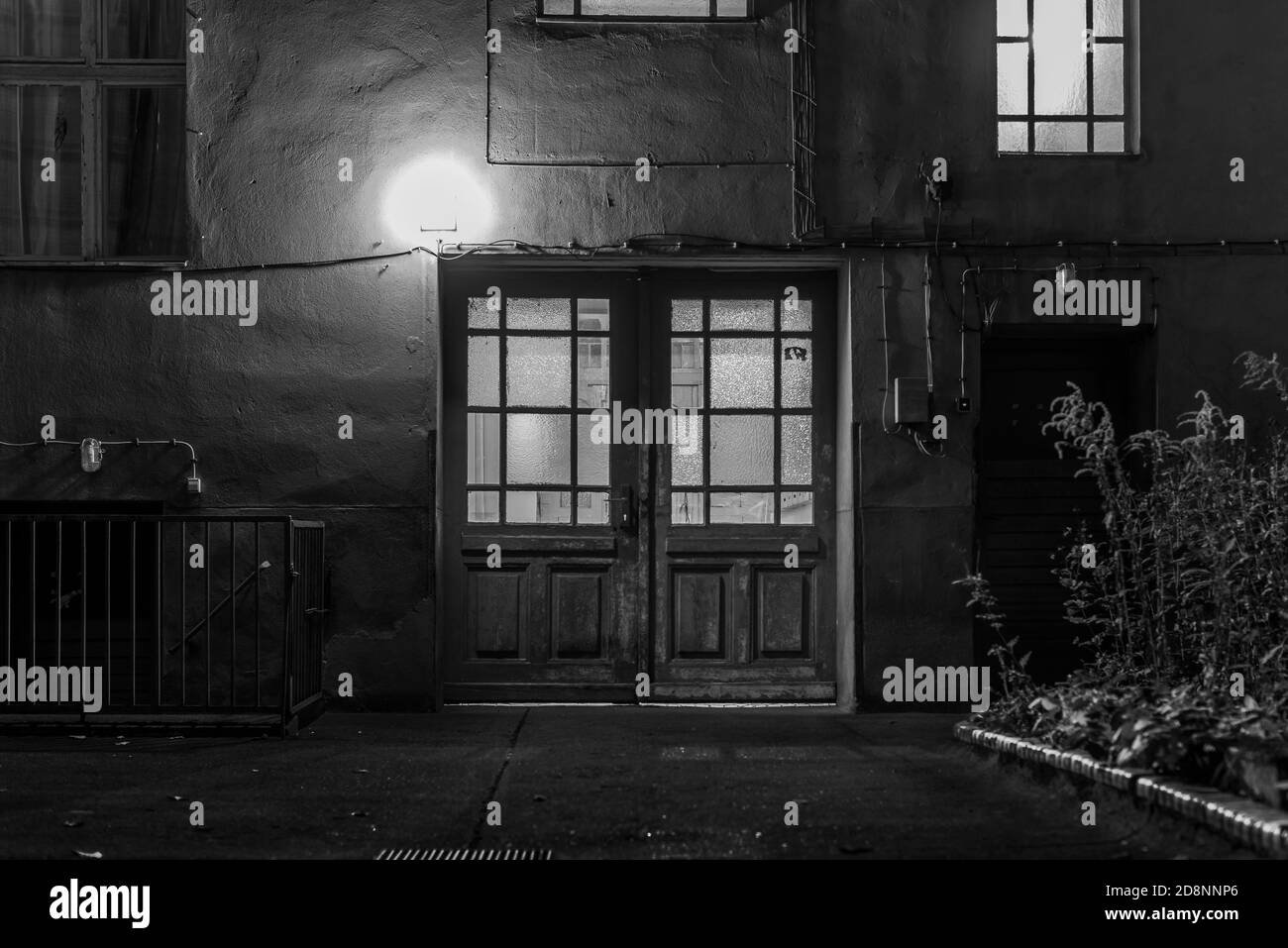 Weathered facade of a house at night, gate of a house passage, unrenovated house in Berlin, at