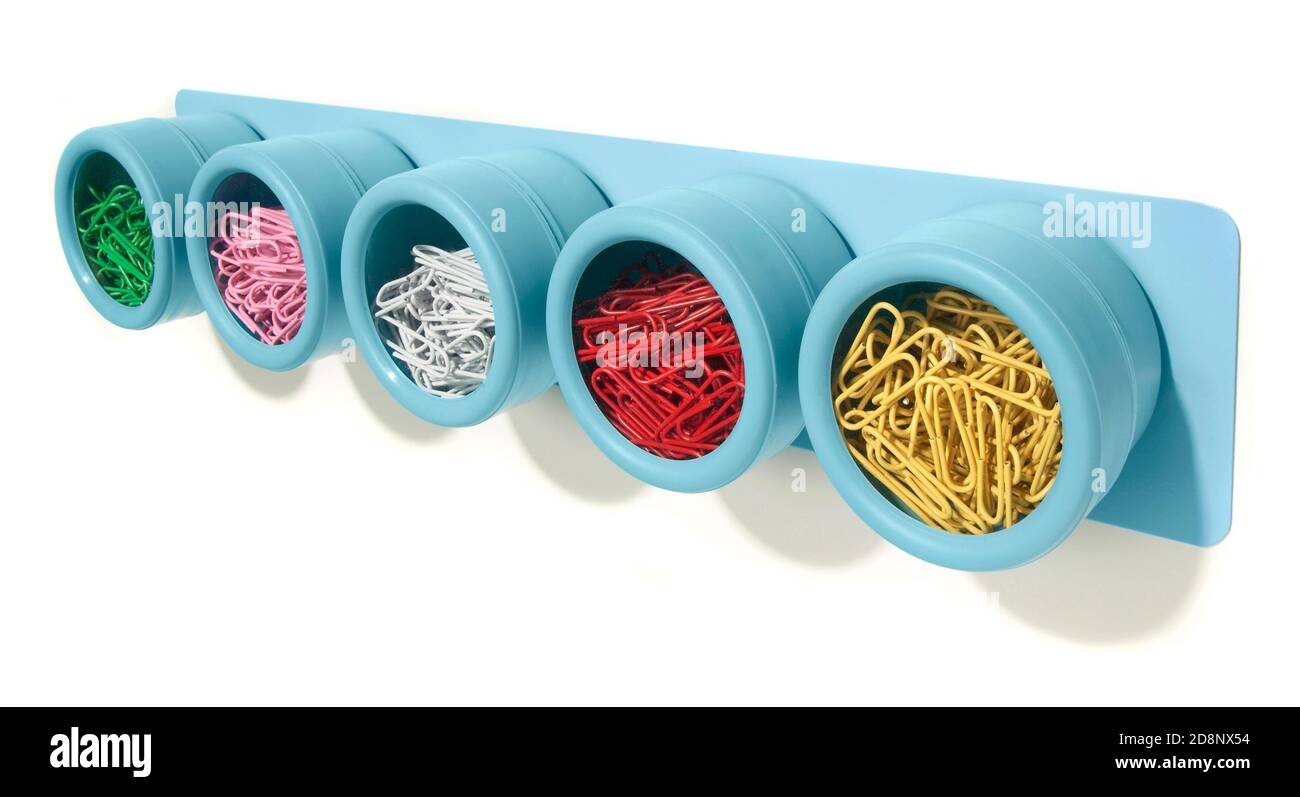 Blue soho spice rack as a paperclip organizer filled with colorful paperclips photographed on a white background Stock Photo